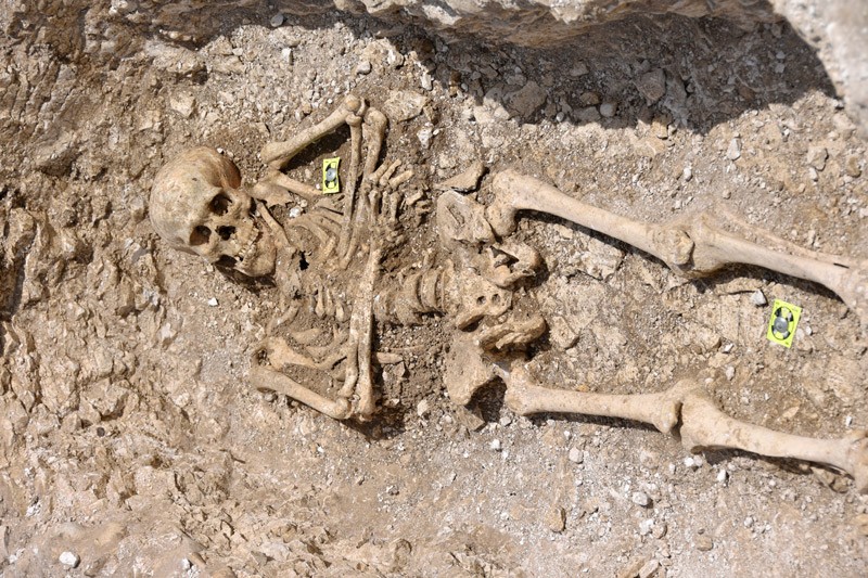 A human skeleton lying straight on the ground with arms folded across the chest