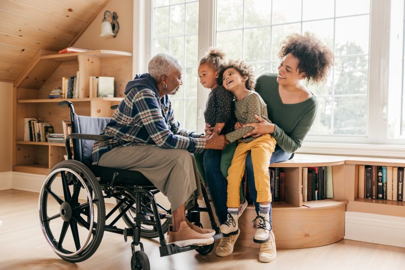 An older lady in a wheelchair engaging with young children