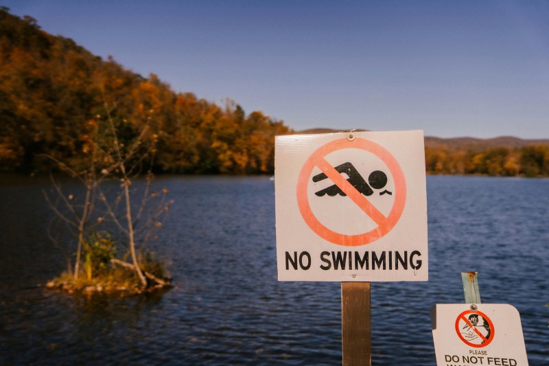 A sign saying no swimming with a lake in the background