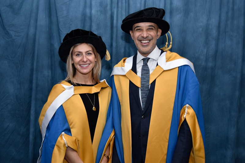 Georgia and Marcus in their ceremonial robes, looking at the camera and smiling