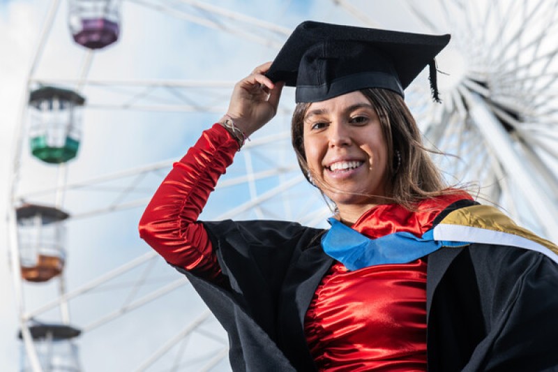 Female student in front of ferris wheel for graduation