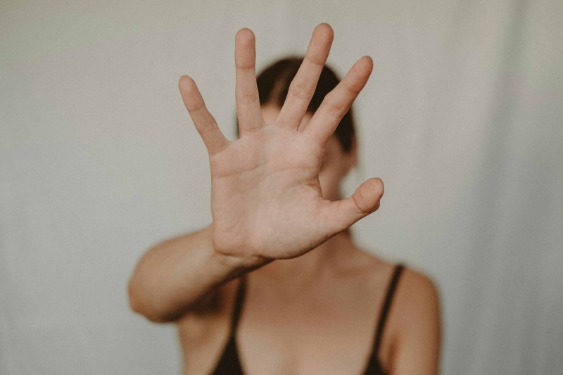 A woman holding her hand in front of her face, indicating to stop