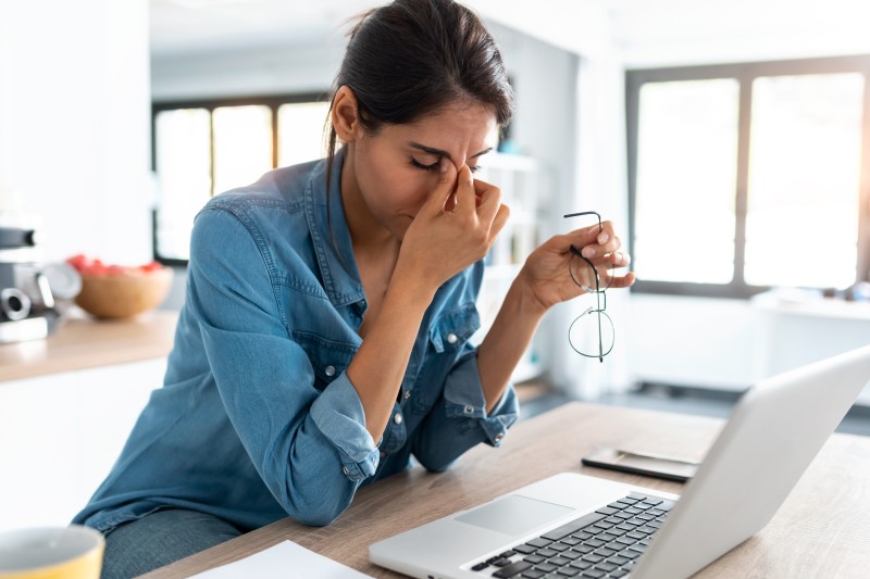 A woman working at home with her head in her hands looking stressed