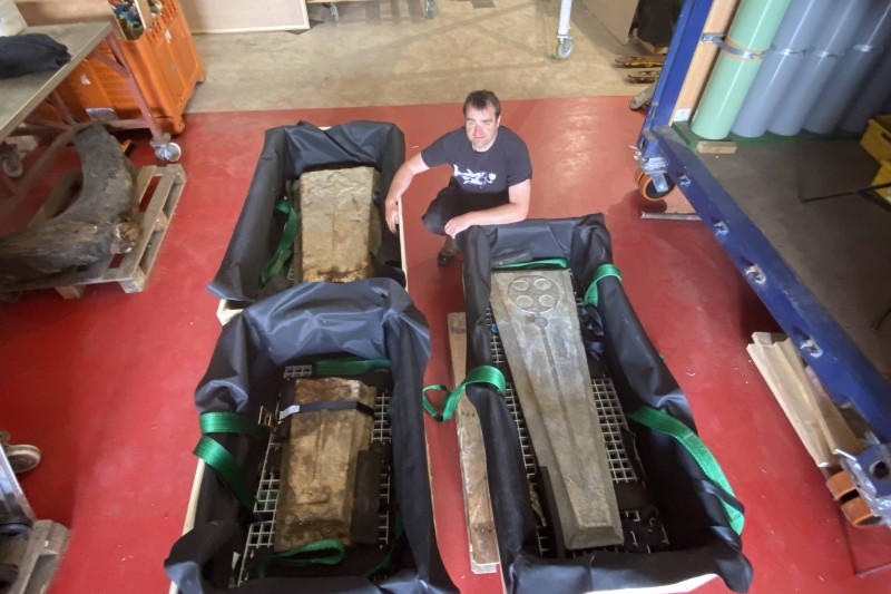 Tom crouching next to three wooden crates, each containing a grave slab