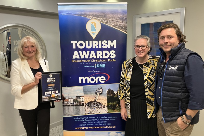 two women and a man standing in front of a banner for the Tourism Awards