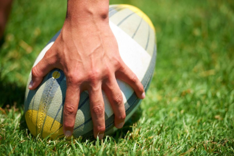 Image of a rugby ball and hand
