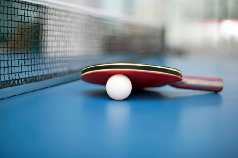Image of a table tennis bat and ball on a table tennis table
