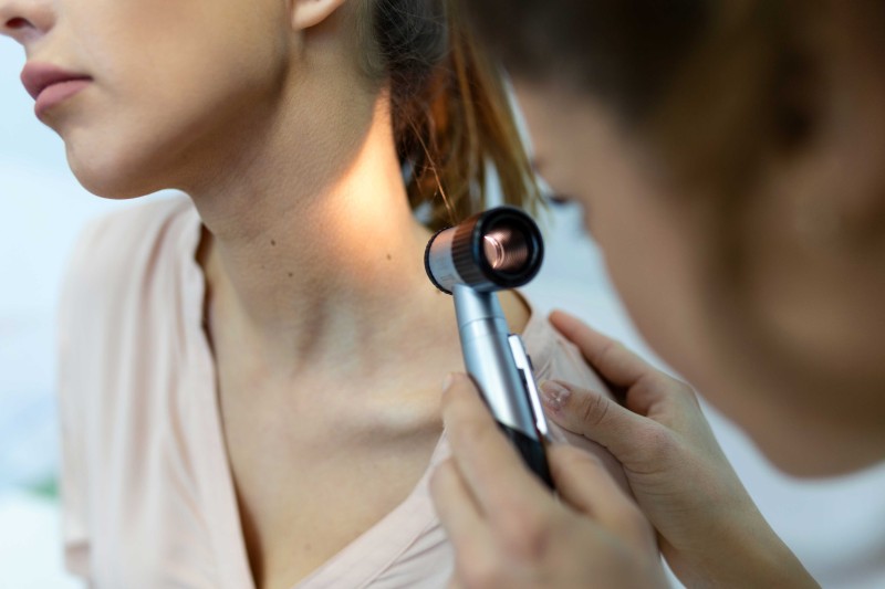 A nurse shining a light onto a mole on a patient